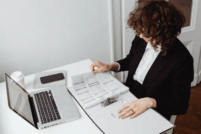 A program administrator reviewing rosters at her laptop in a bright office